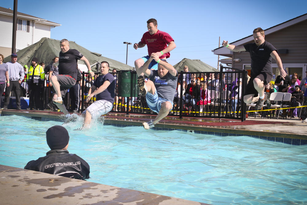 Male officers jumping into a pool