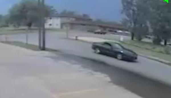 Dark colored 2-door vehicle driving down the street