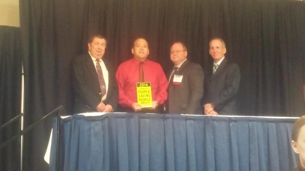 4 men, including Sheriff Groves, standing behind a table on a stage