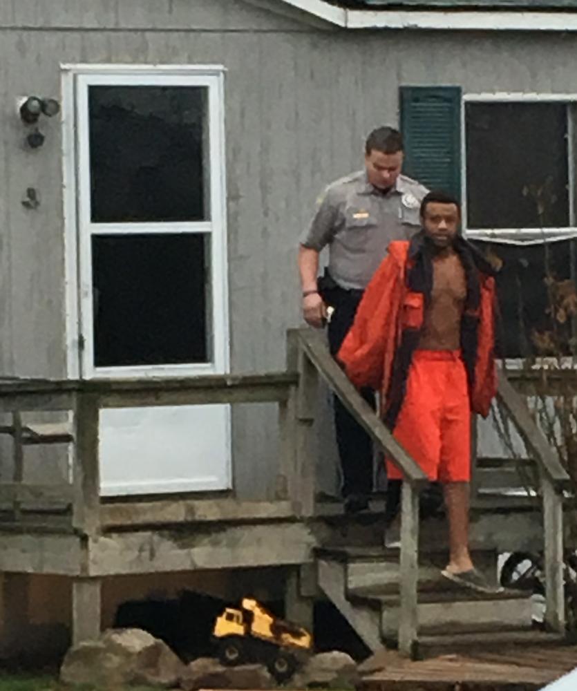 Officer and man wearing winter coat and red shorts, leaving residence