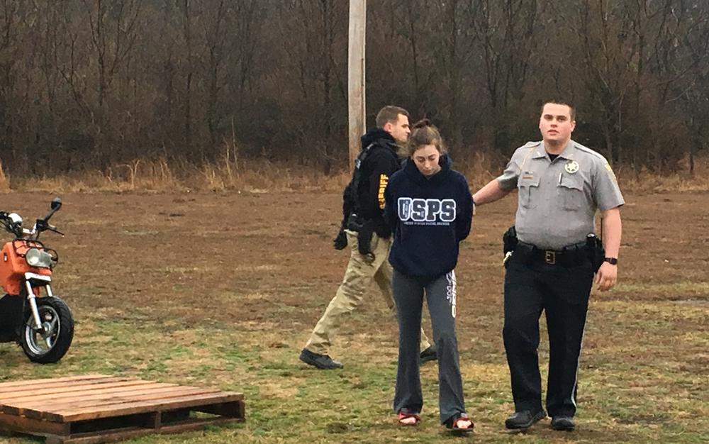 Officer escorting handcuffed suspect off the scene