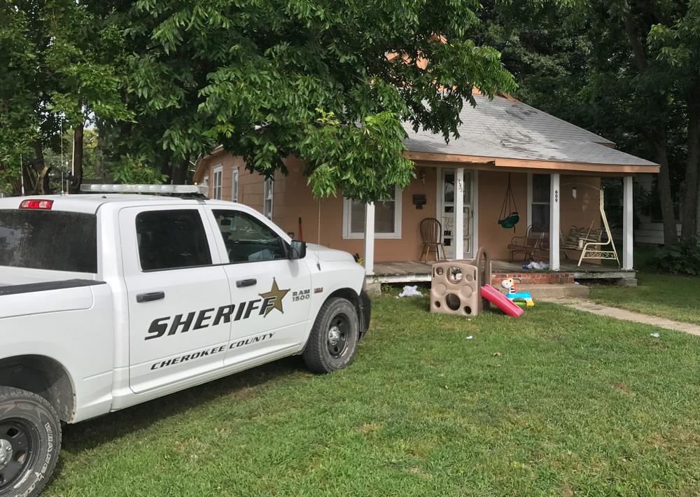 police vehicle outside residence with child slide and toys in front yard