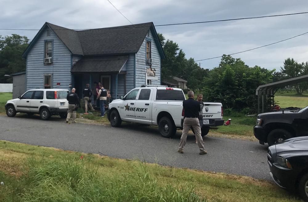 several police vehicles parked in front of residence and many officers standing around