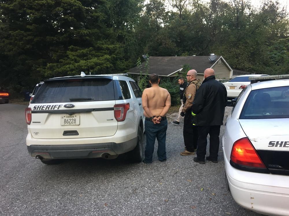 Officers standing with handcuffed man