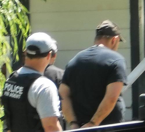 Police officer standing behind arrested man